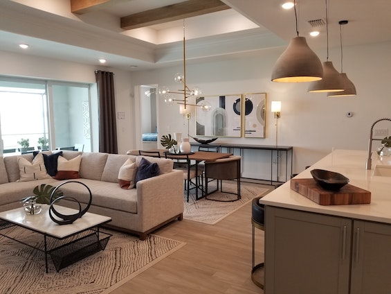 furnished living room, dining room and kitchen complete with a couch, coffee table, dining table and bar stools